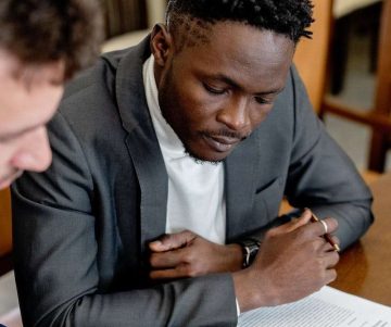 A Man in Gray Suit Looking at the Tablet on a Wooden Table